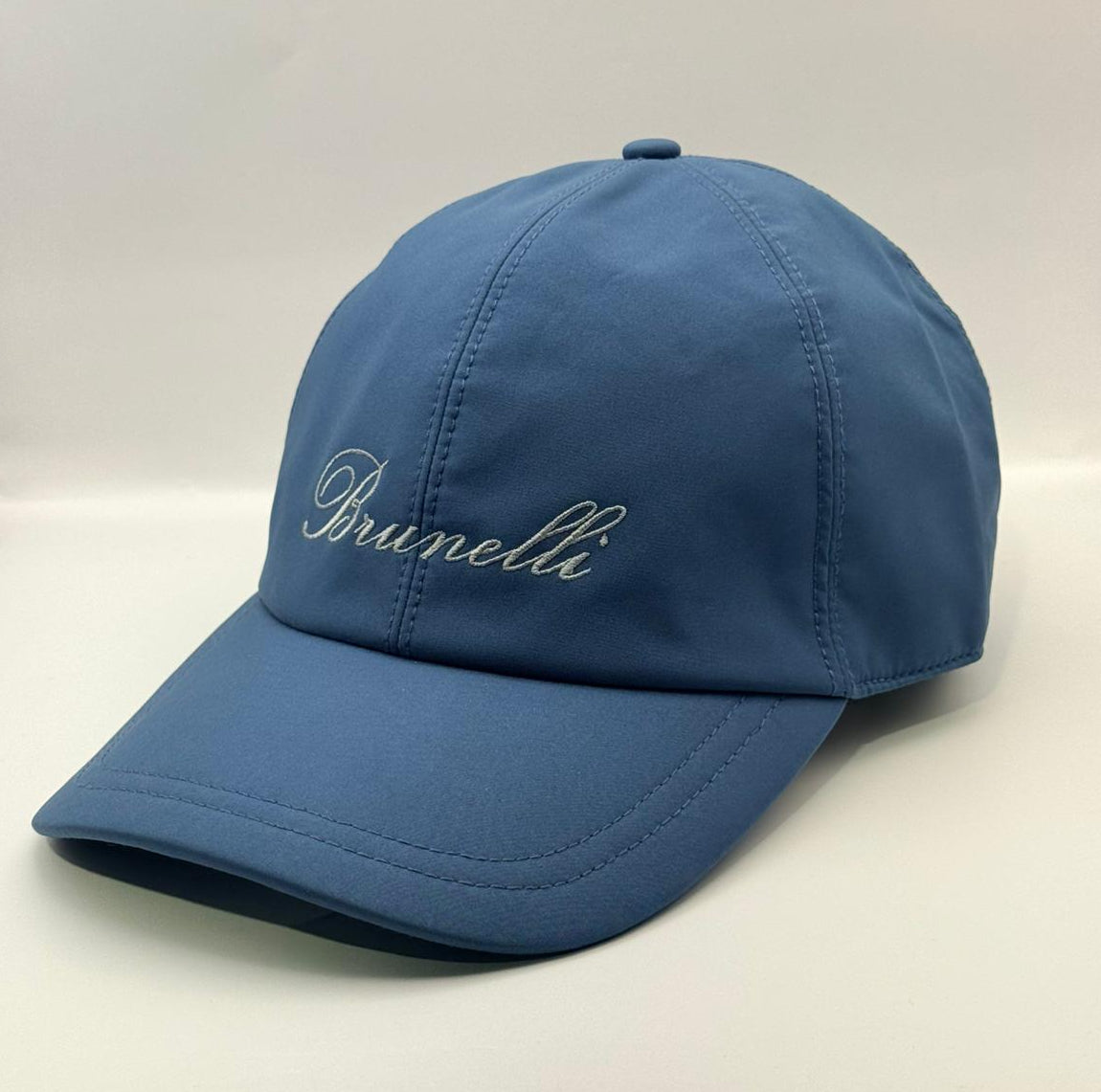 Blue cap with 'Brunelli' branding on a white background